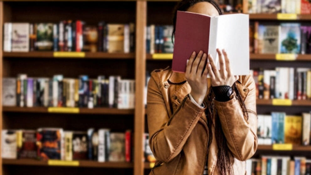 Девушка в библиотеке с книгой